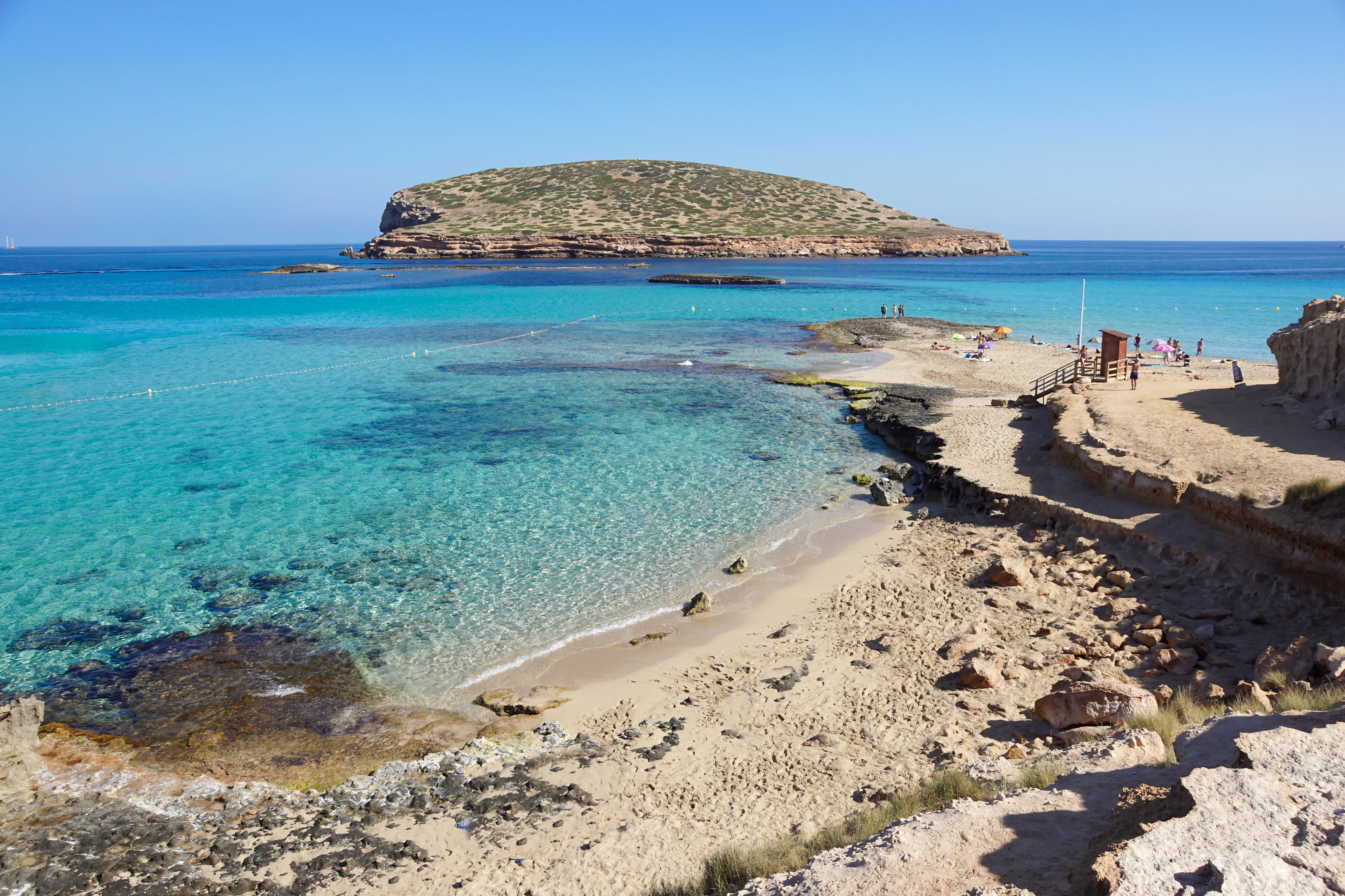 Strand mit türkisem Wasser und weißem Sandstrand vor schroffen Klippen