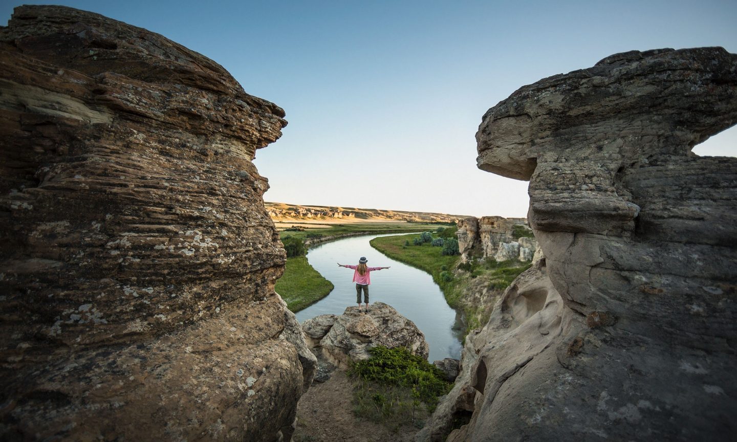 A woman standing between two rocks and looking at the landscape