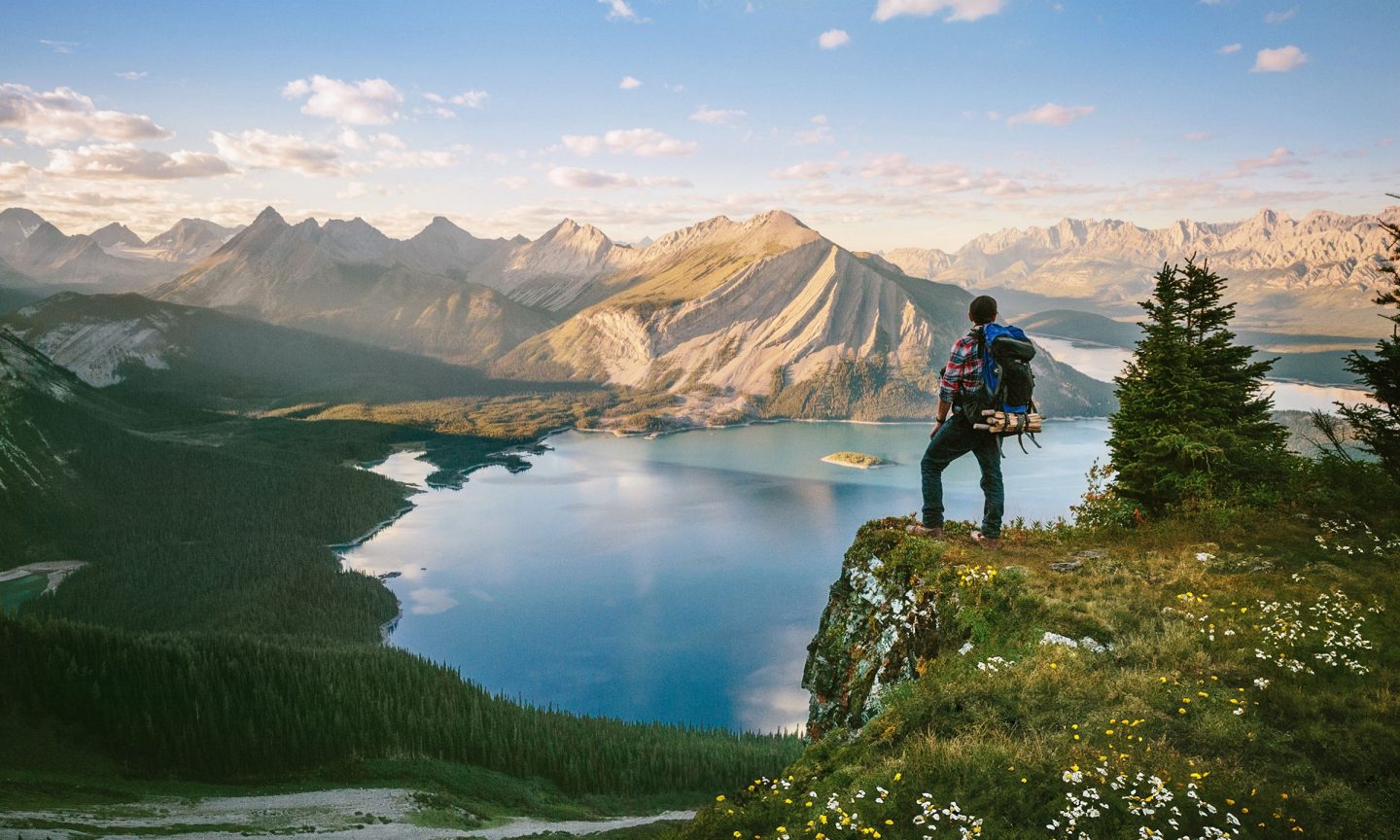 A hiker standing on a cliff and looking down at a lake