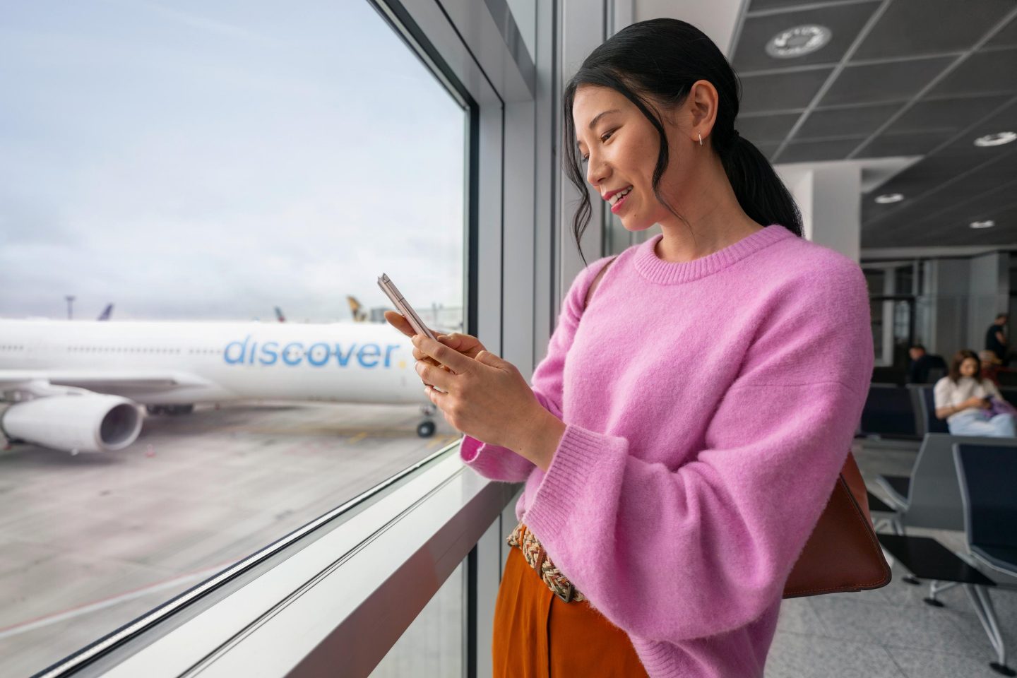 Eine Frau steht am Gate und schaut auf ihr Handy