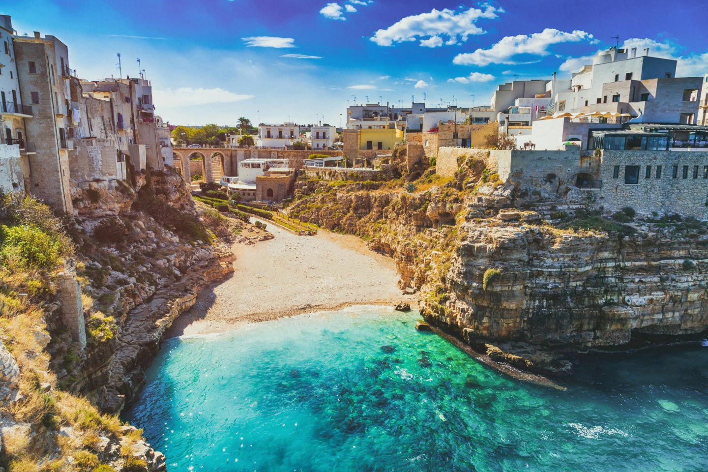 Sandstrand zwischen Felsen und Häusern in Bari