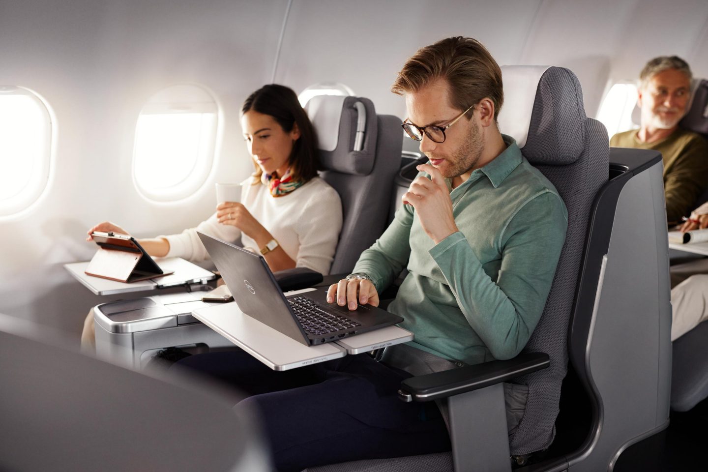 Internet an Bord Zwei Gäste sitzen in der Business Class und schauen auf einen Laptop und ein Tablet