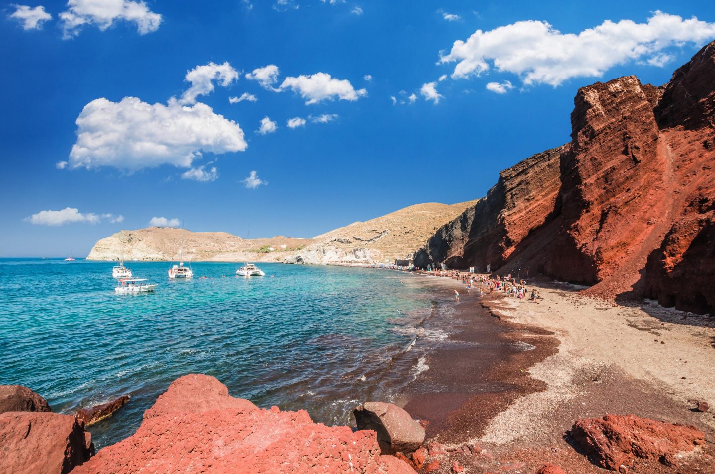 Sandstrand mit roten Steinklippen auf Santorini