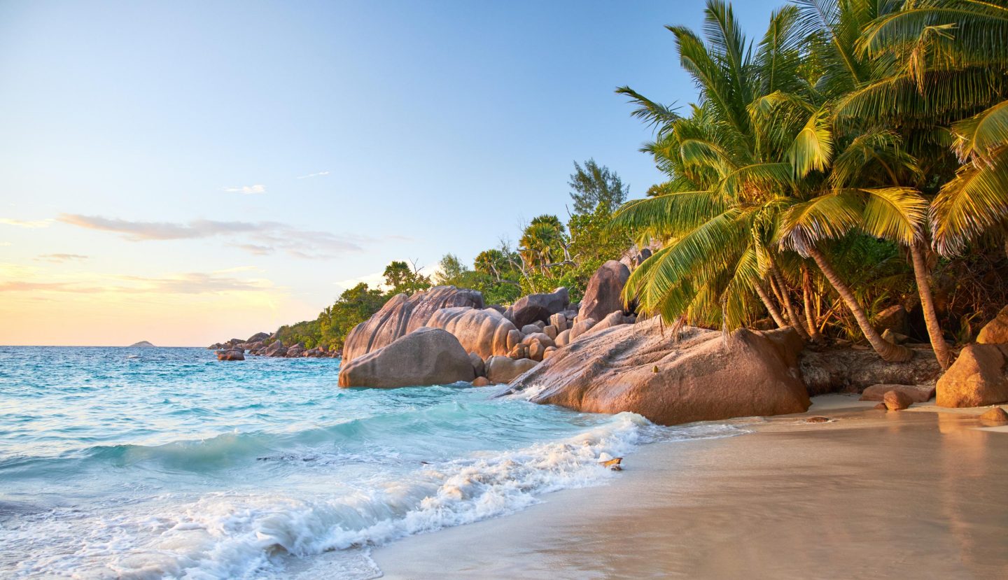 On a beach in the Seychelles with rocks and palm trees