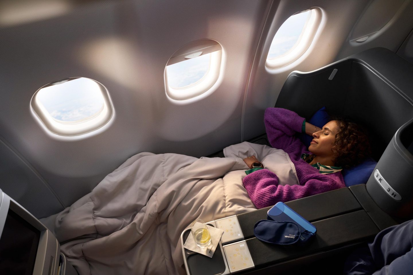 Business Class Interkont Eine Frau liegt auf einem Sitz in der Business Class mit einer Decke