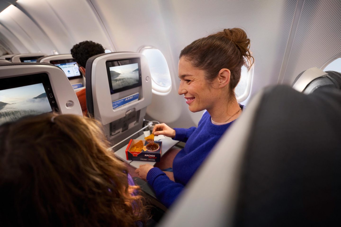 Economy Class Interkont Eine Frau isst einen Snack aus der Onboard Bar in der Economy Class