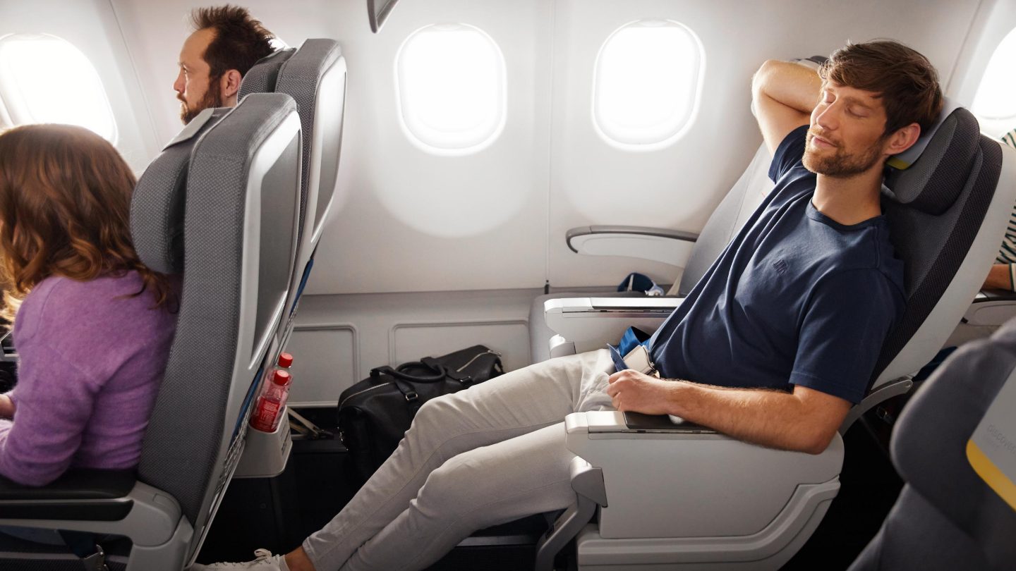 A man sits in Economy Class in the Extra Legroom section