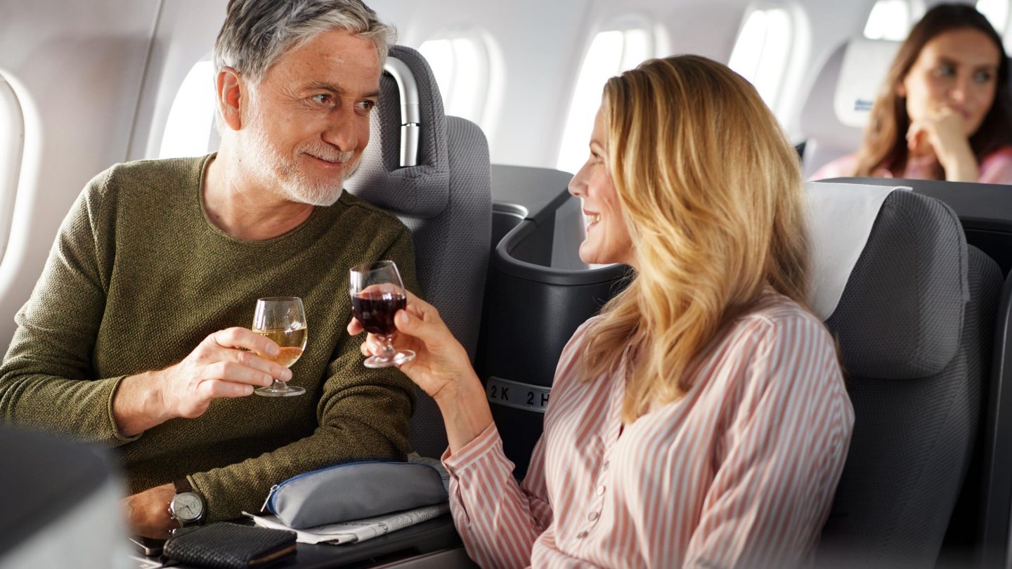A couple toasts with red wine in Business Class