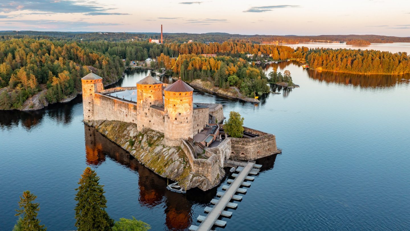 Burg Olavinlinna bei Savonlinna, umgeben von Seen und herbstlichen Wäldern.