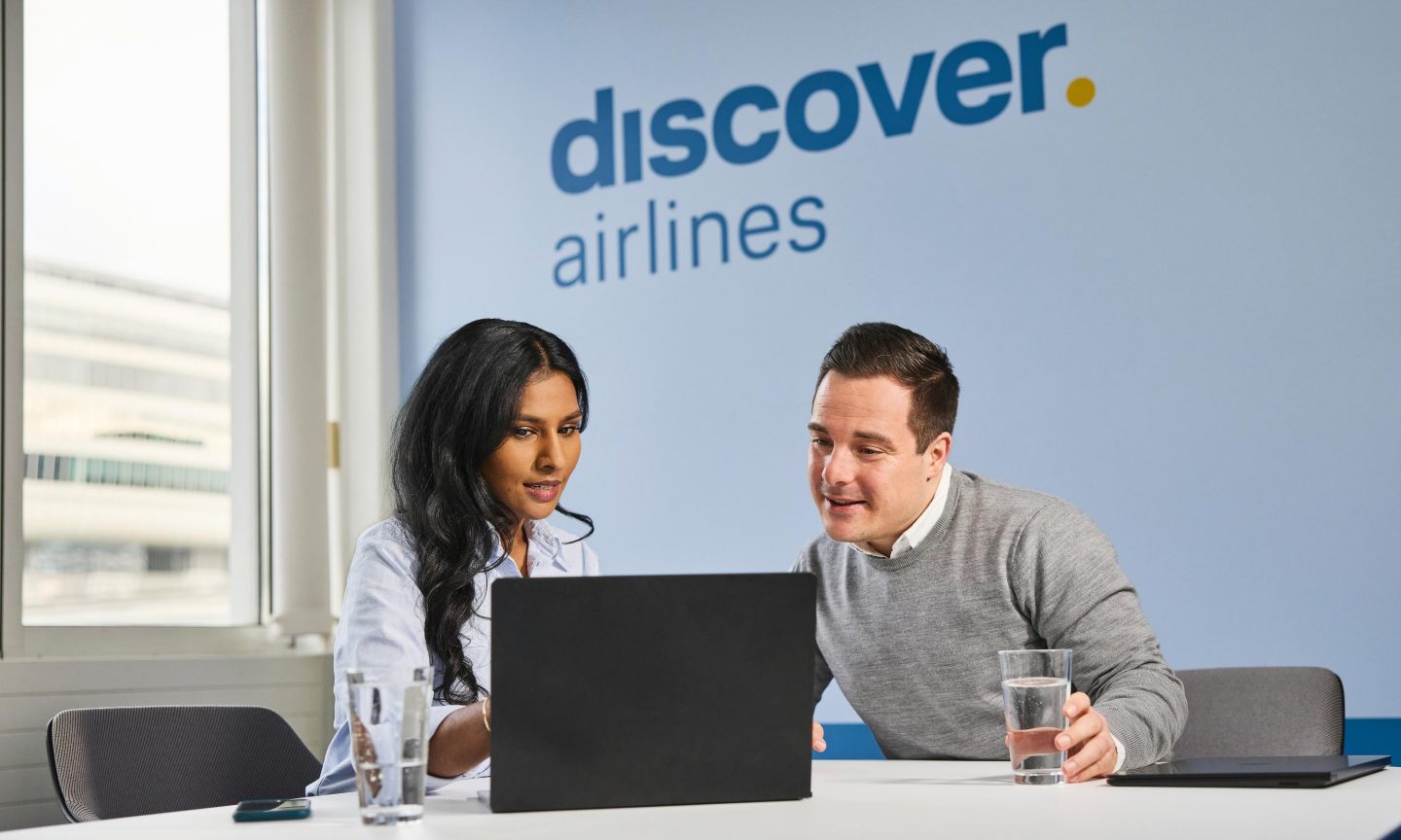 Zwei Discover Airlines Mitarbeitende schauen auf einen Laptop