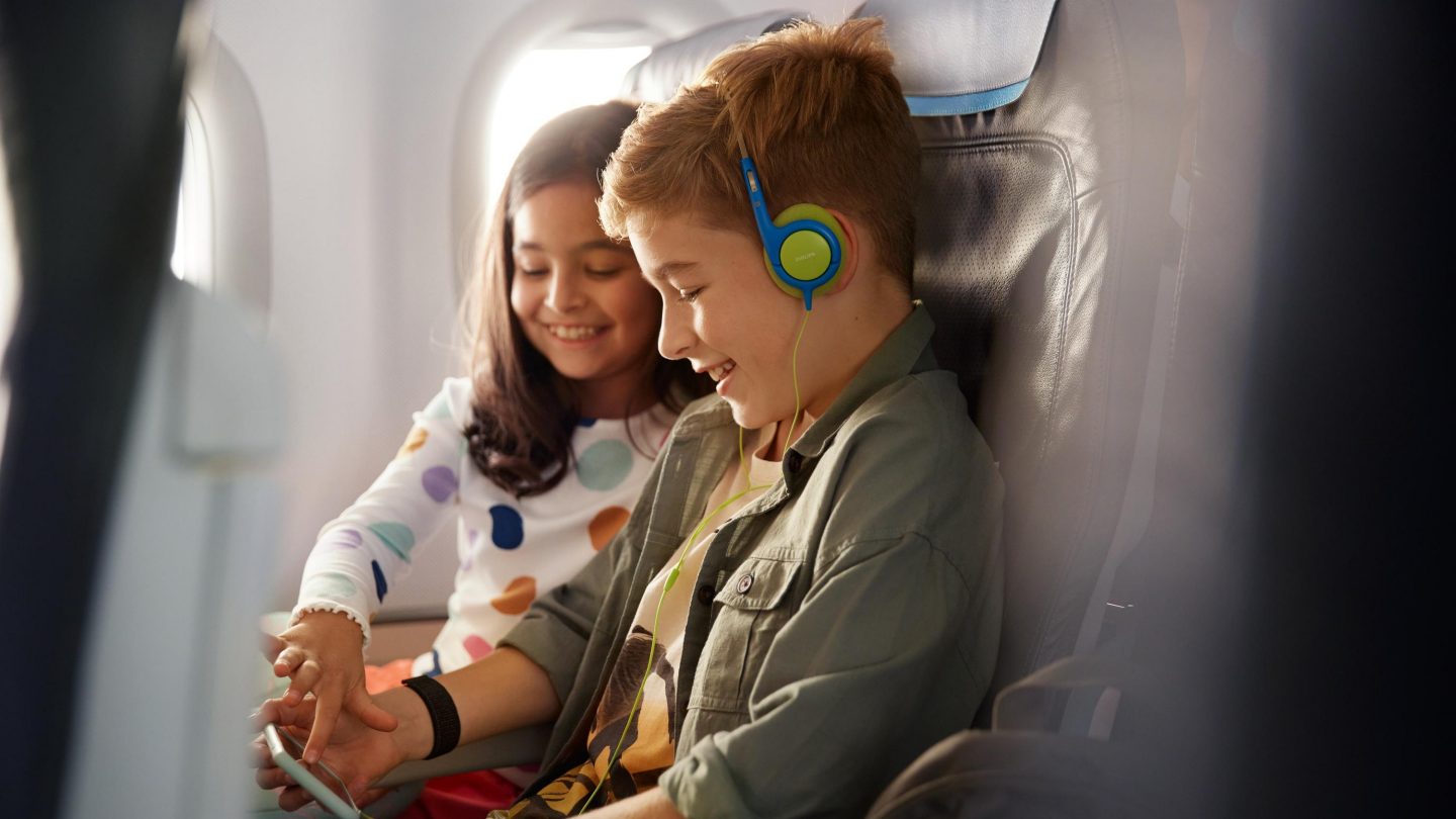 Two children are sitting in Economy Class, enjoying the entertainment on the Onboard Cloud