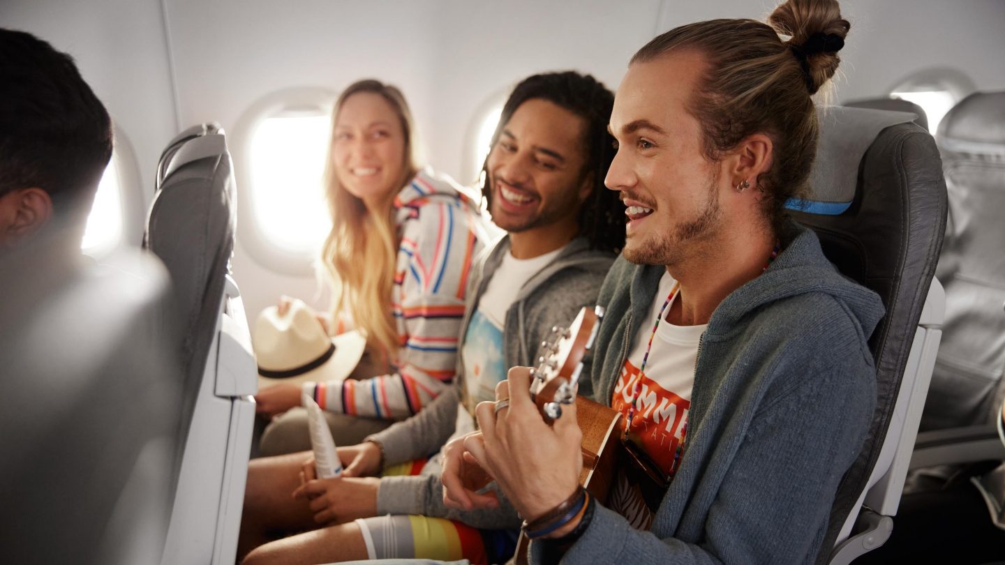 Drei Gäste sitzen in der Economy Class nebeneinander