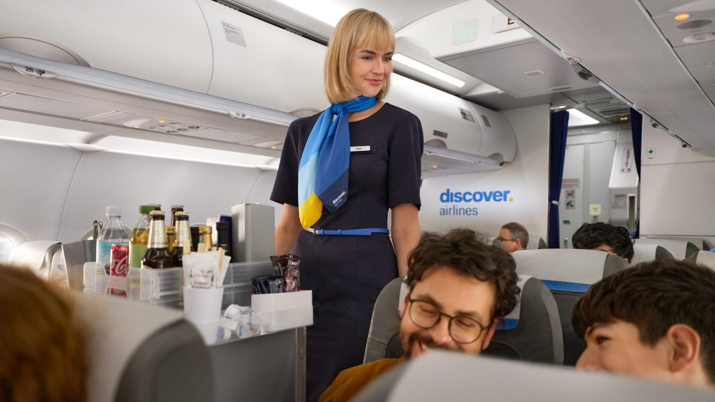 Eine Cabin Managerin im Gang der Economy Class
