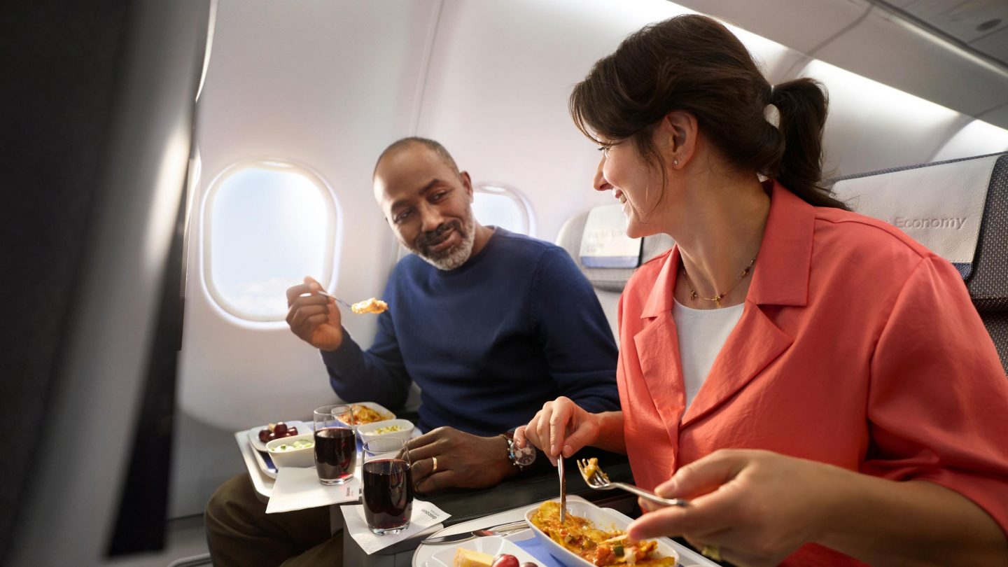 Ein Paar sitzt in der Premium Economy Class uns isst ein leckeres Menü