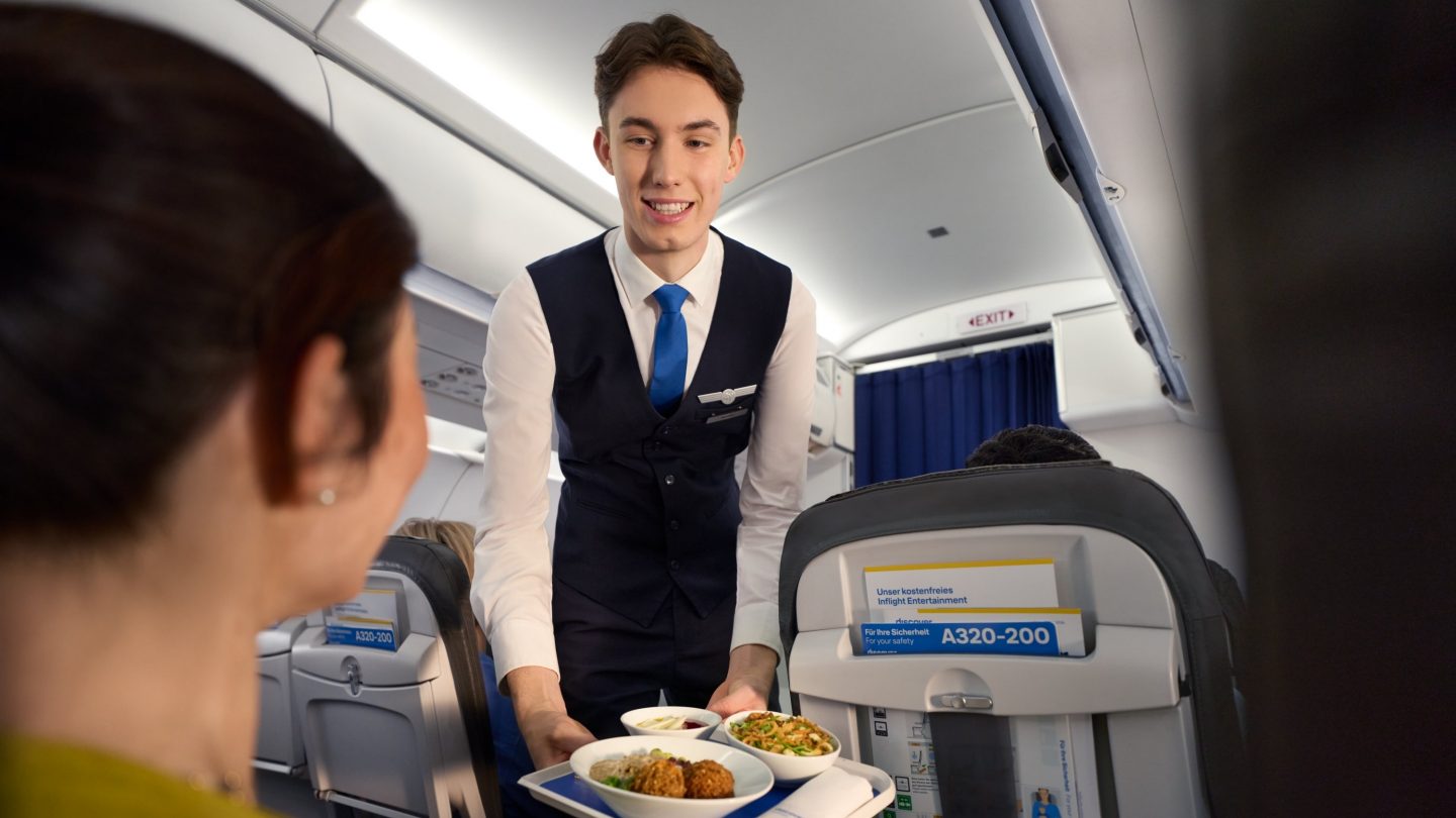 Eine Frau bekommt in der Discover Airlines Business Class ein warmes Menü serviert