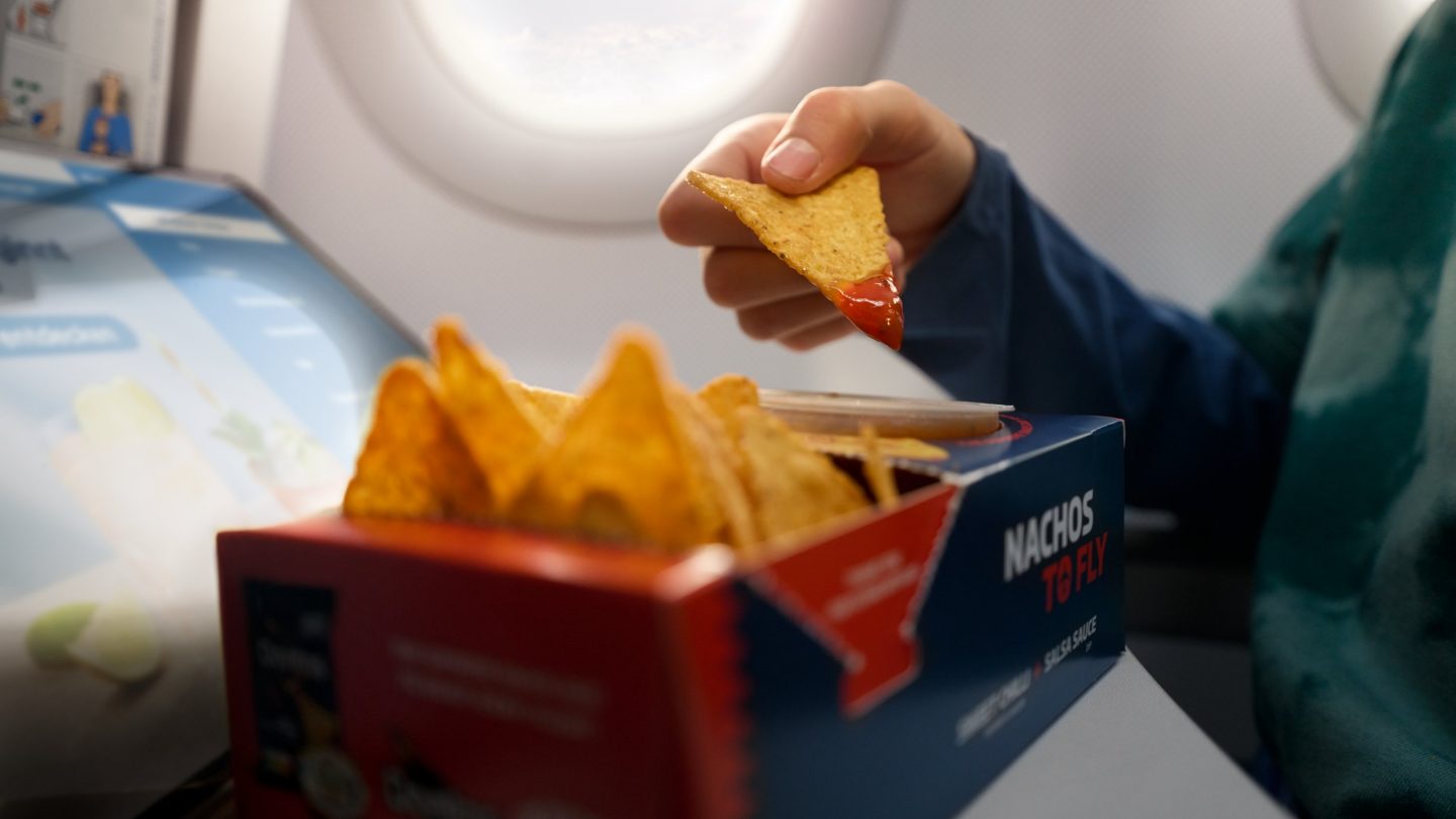 Un enfant mange des nachos et regarde l'Onboard Cloud à bord