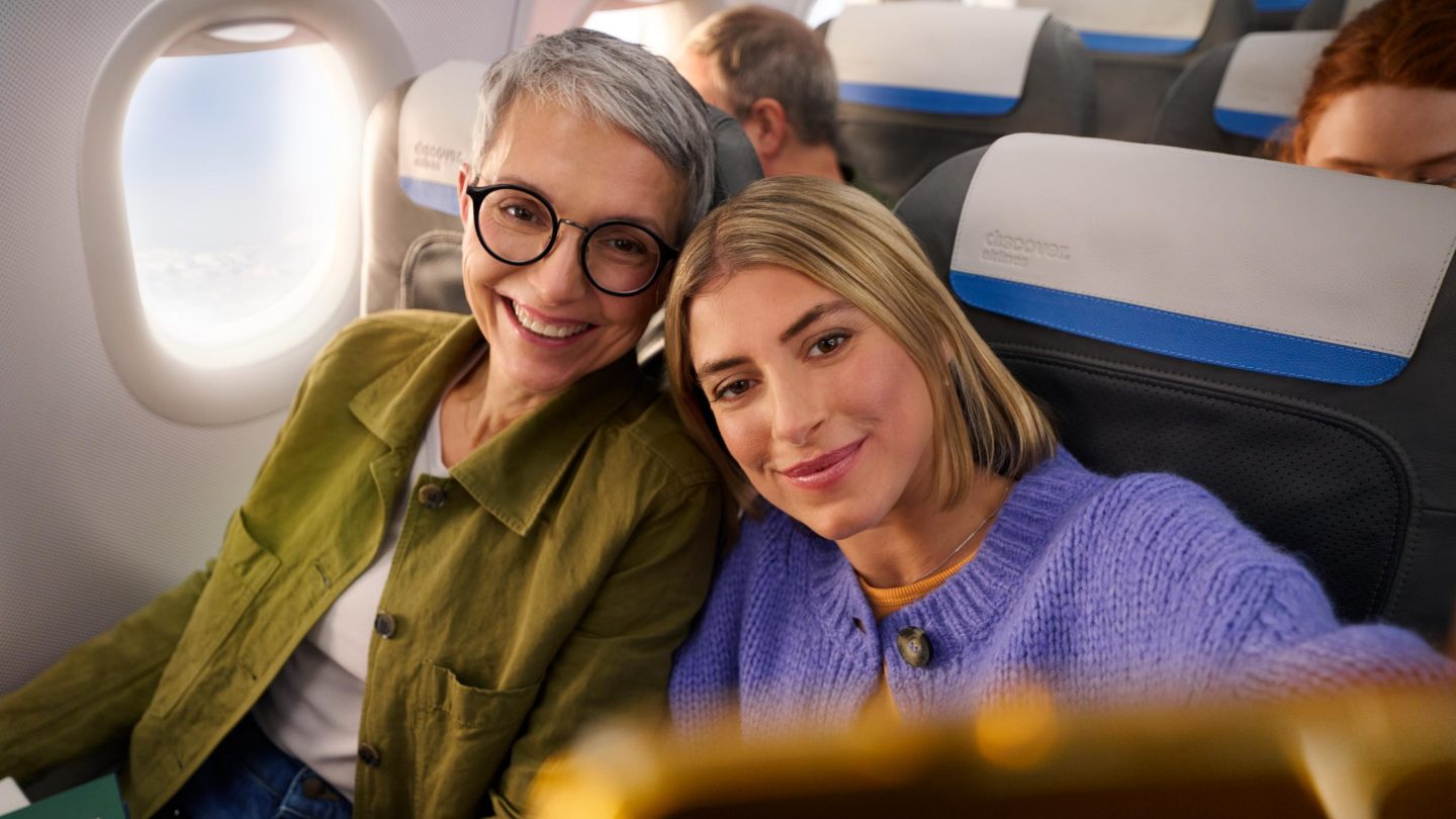 A mother and daughter are taking a selfie in Economy Class.