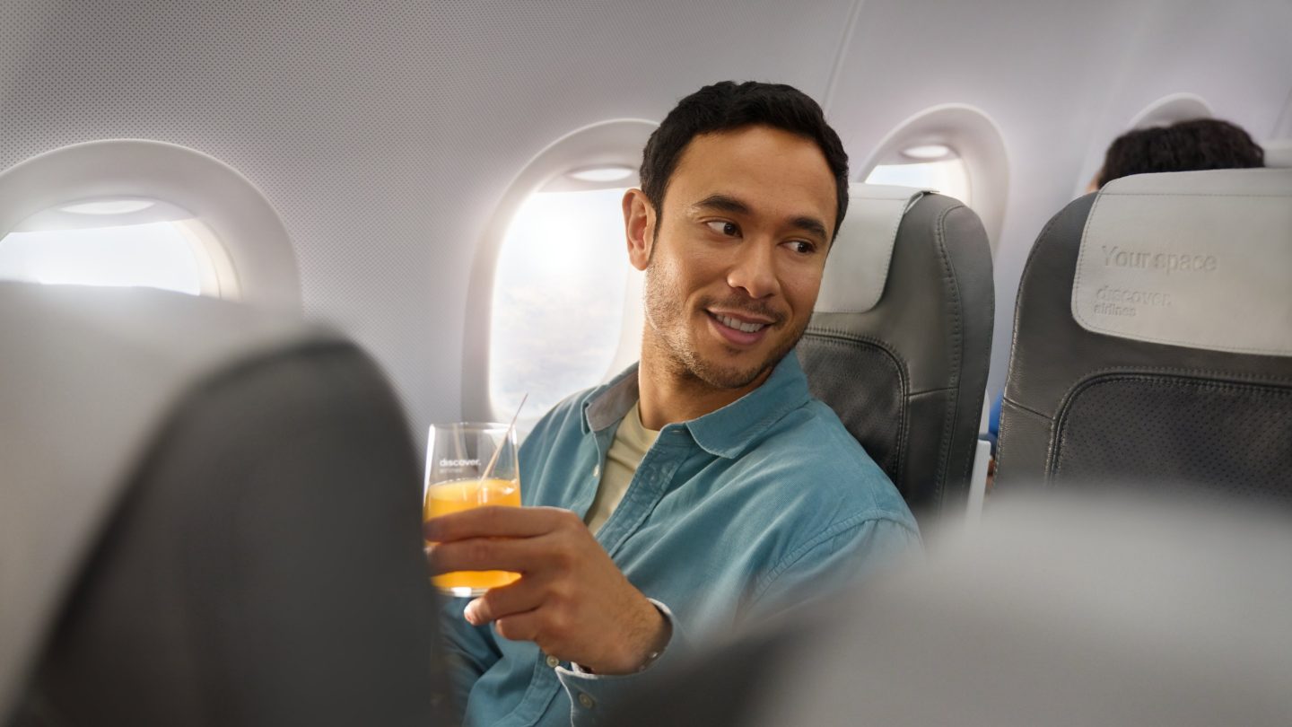 A man sitting in Business Class on an A320 has a Welcome Drink in his hand