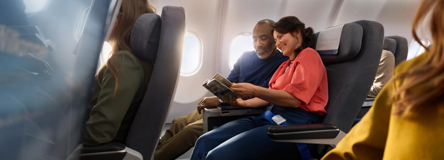 Ein Paar macht es sich in der Premium Economy Class bequem mit viel Beinfreiheit