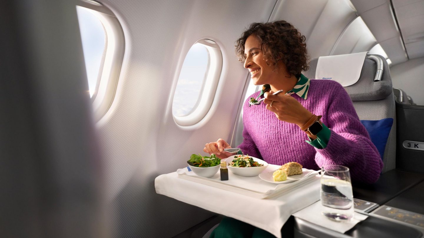 A woman sits in Business Class and eats a meal