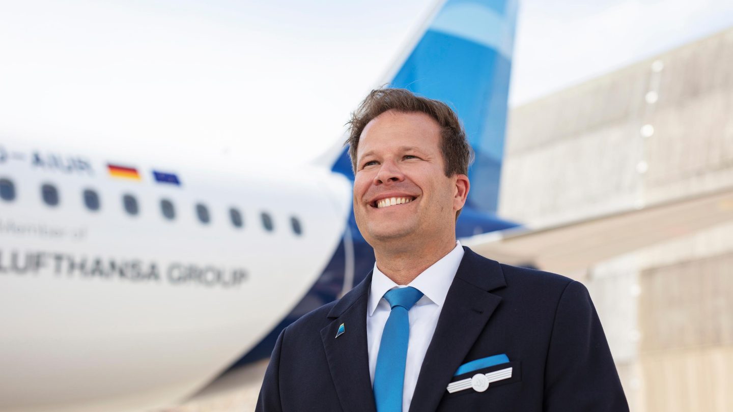 A pilot is standing in front of a Discover Airlines A320