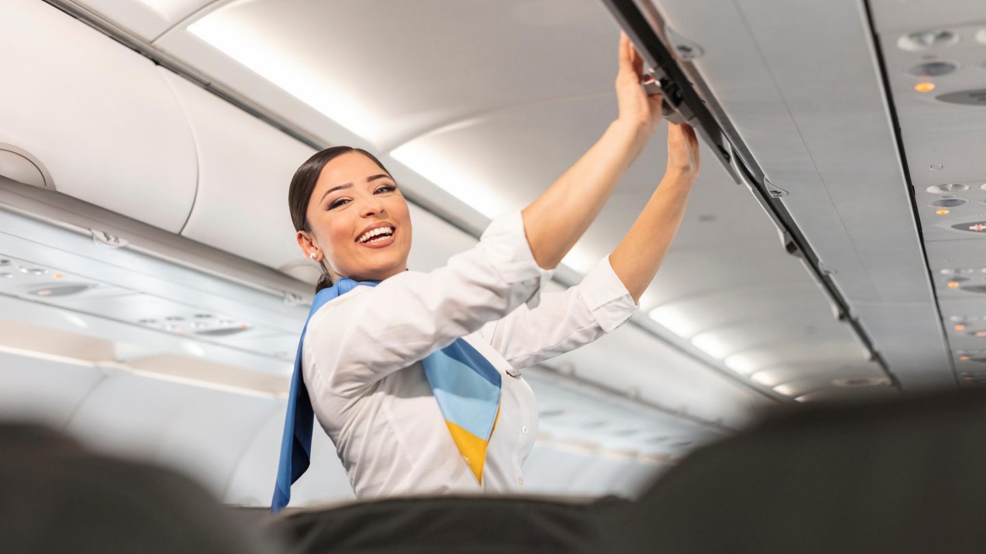 A cabin manager closes a bin on the aircraft