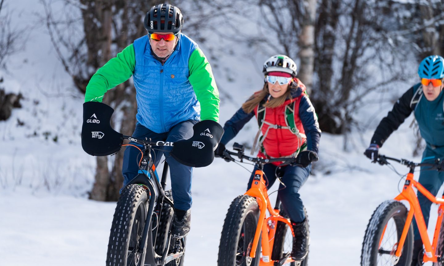 Three people riding bicycles through the snow