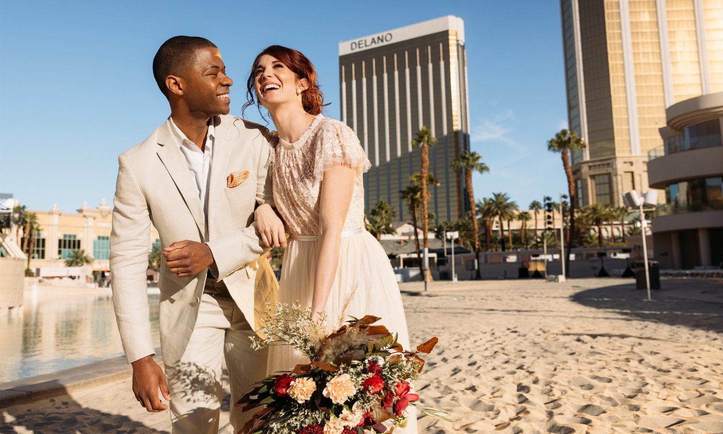 Newlywed couple laughs and stands on the beach