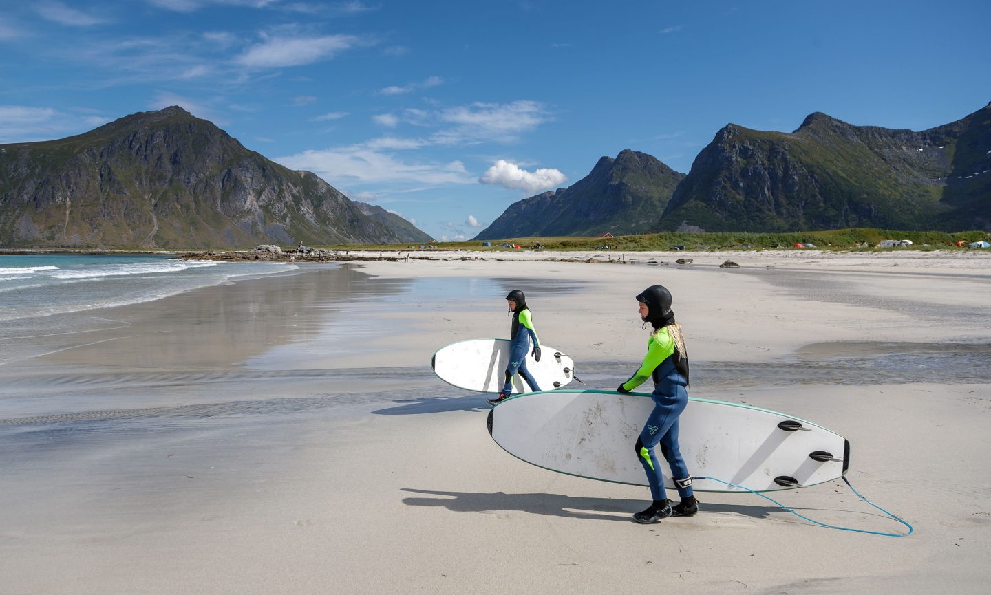 Zwei Kinder in Neoprenanzügen gehen surfen