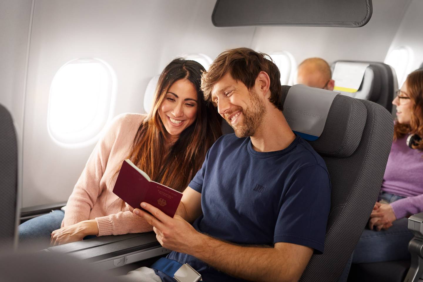 Couple looking at a passport and sitting in Premium Economy Class Longhaul