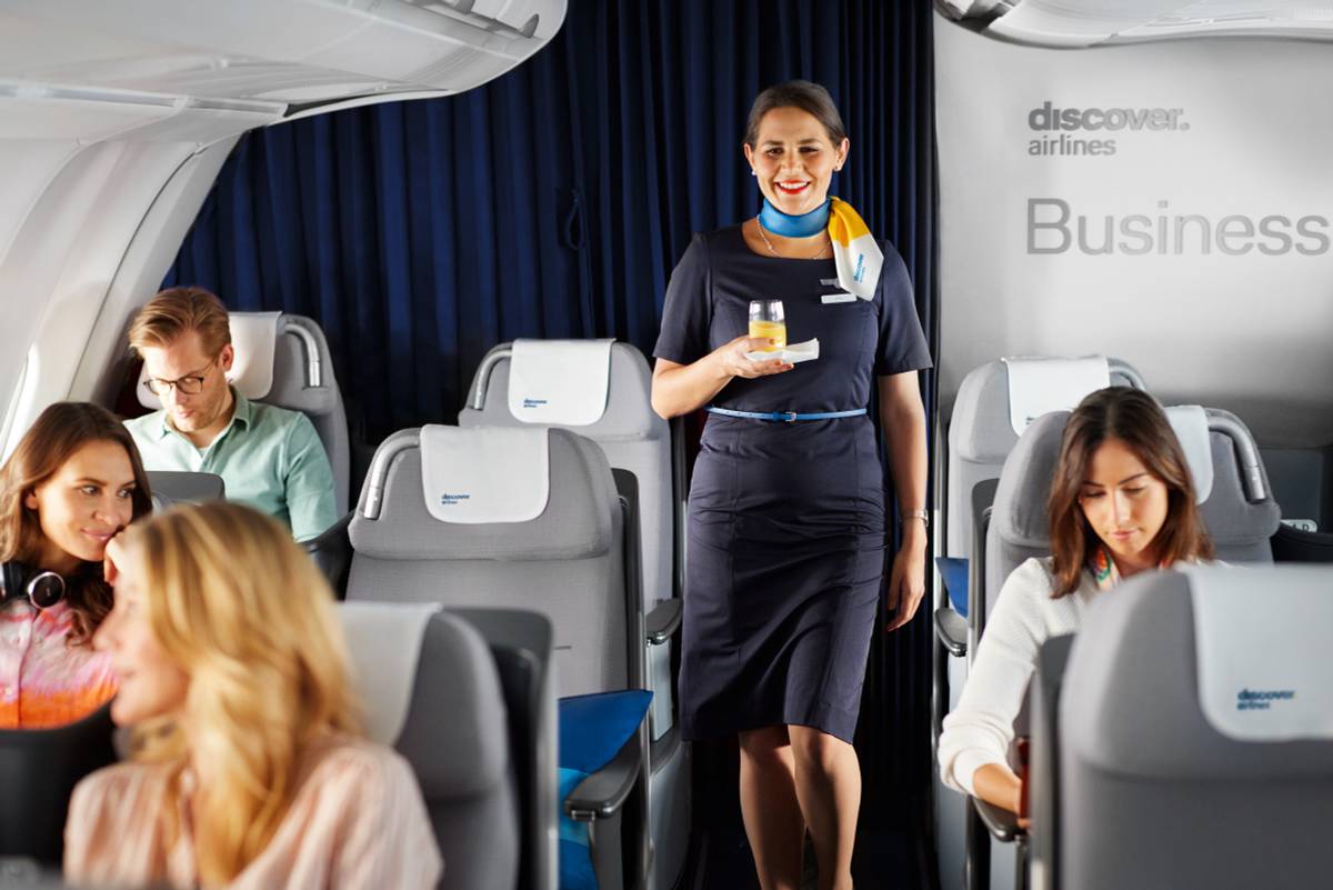 A cabin manager serves a drink in Business Class