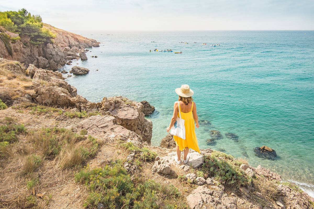 Woman in a yellow dress walks along the sea