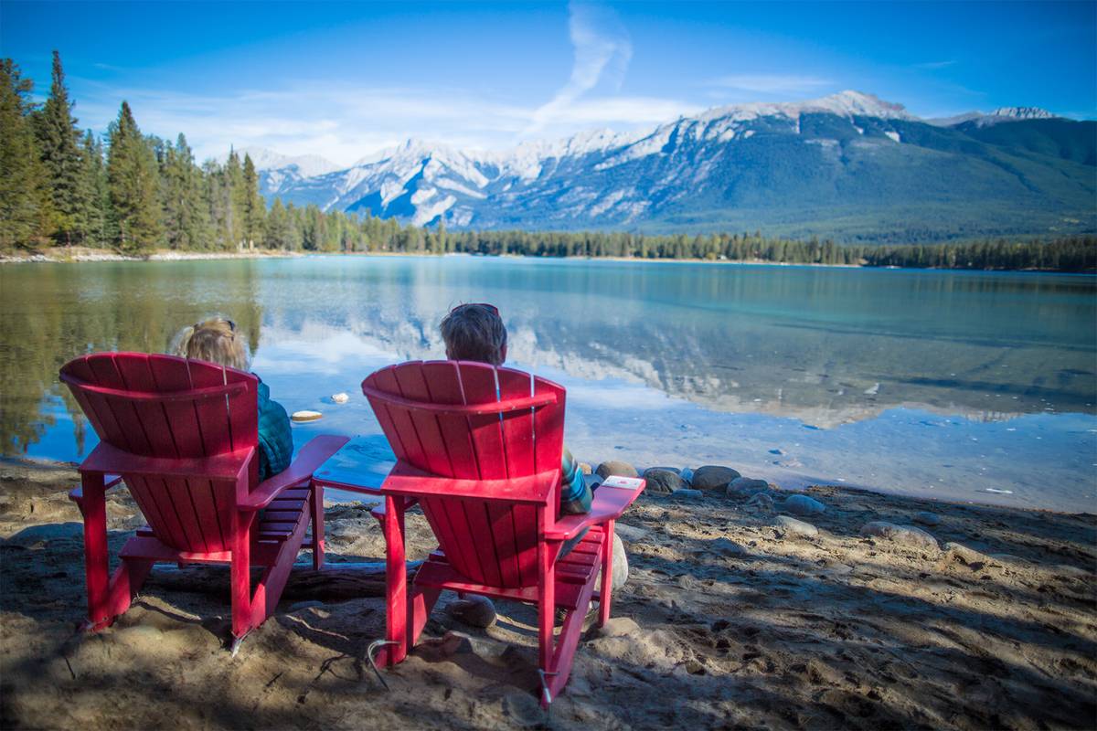 Man and woman sit on deckchairs and look out over the Alberta landscape