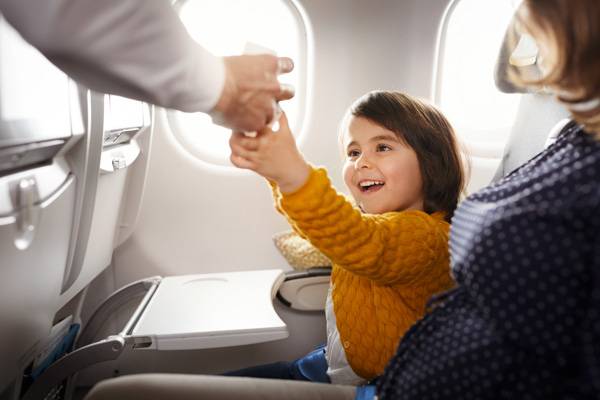 A child reaches for a drink in economy class