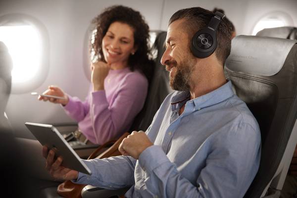Mann und Frau sitzen im Flugzeug und schauen auf ein Tablet