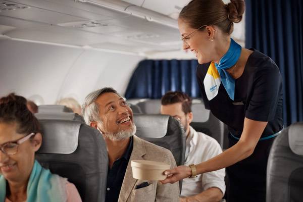 Flugbegleiterin bringt Fluggast etwas zu essen