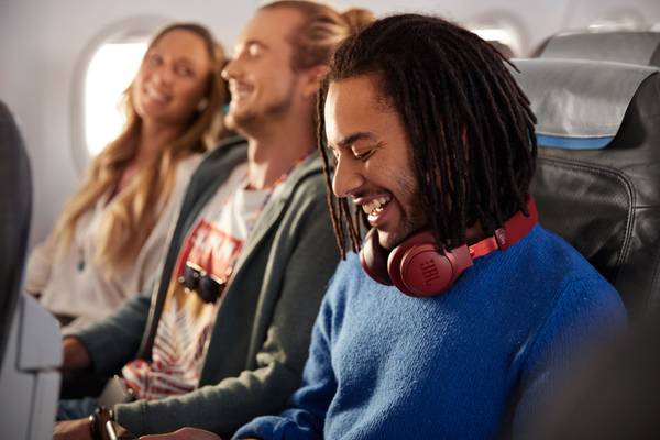 Drei junge Menschen sitzen im Flugzeug in einer Reihe und lachen