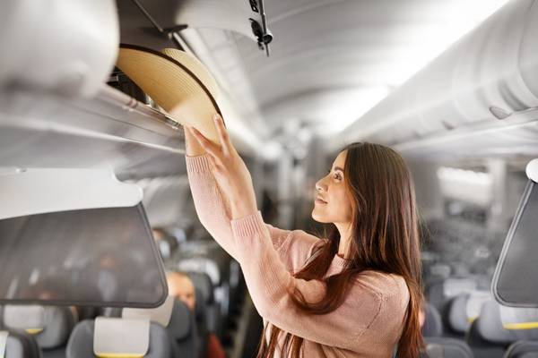 Frau verstaut ihr Handgepäck im Flugzeug