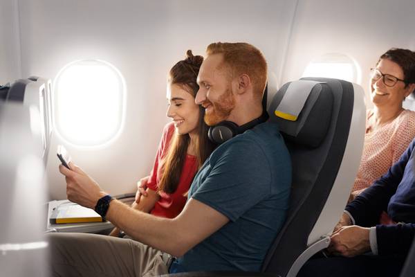 Ein Mann und eine Frau sitzen im Flieger und schauen auf ein Tablet