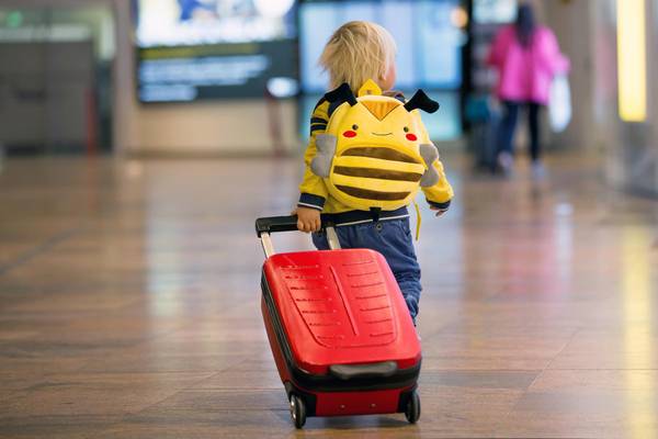 Kleinkind am Flughafen mit Koffer und Rucksack