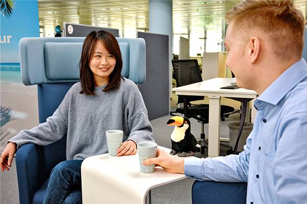 Mann und Frau sitzen im Discover Airlines Office und trinken Kaffee