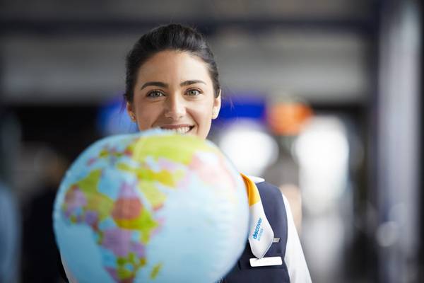 A flight attendant holding a globe in her hand.