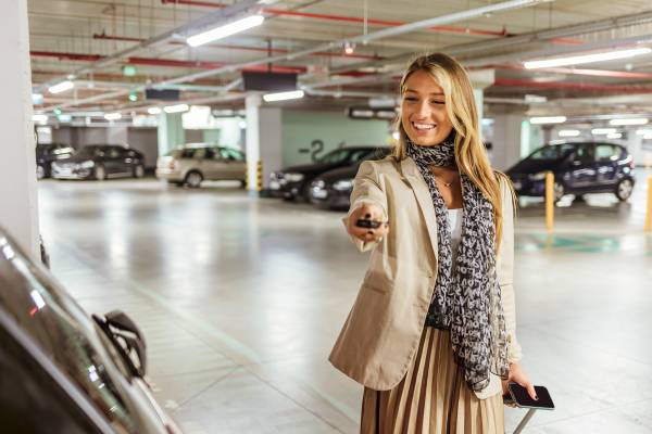 A woman unlocks her car in the parking garage